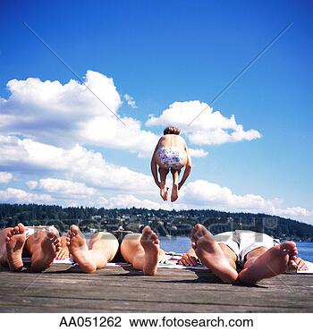 Stock Photo - teenagers (14-16) 
lying on dock, 
girl jumping into 
lake, rear view. 
fotosearch - search 
stock photos, 
pictures, images, 
and photo clipart