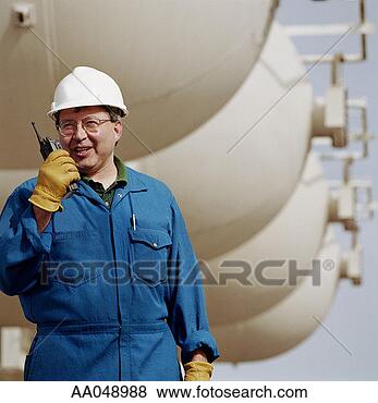 Stock Photo - man wearing hard 
hat, using walkie 
talkie at oil 
refinery. fotosearch 
- search stock 
photos, pictures, 
images, and photo 
clipart