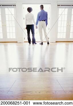 Stock Photography - couple looking 
out french doors 
of house, rear, 
low angle view. 
fotosearch - search 
stock photos, 
pictures, images, 
and photo clipart