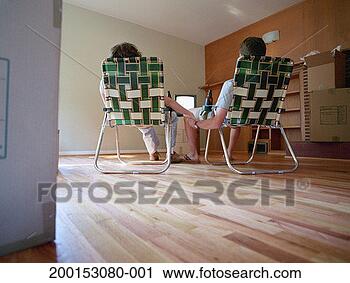 Stock Photography - couple sitting 
on deck chairs 
in empty room, 
watching tv, rear 
view. fotosearch 
- search stock 
photos, pictures, 
images, and photo 
clipart