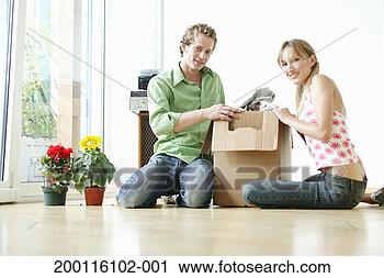 Stock Photography - young couple sitting 
on floor beside 
open packing box, 
portrait. fotosearch 
- search stock 
photos, pictures, 
images, and photo 
clipart