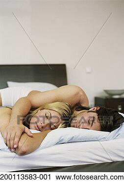 Stock Photography - young couple in 
bed, man embracing 
woman, eyes closed. 
fotosearch - search 
stock photos, 
pictures, images, 
and photo clipart