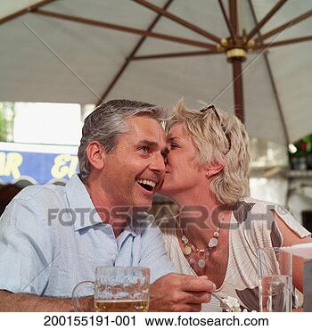 Stock Photography - mature couple 
at outdoor bar, 
woman whispering 
in man's ear, 
close-up. fotosearch 
- search stock 
photos, pictures, 
images, and photo 
clipart