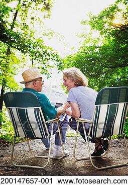 Stock Photography - senior couple 
sitting on deck 
chairs, man holding 
newspaper, rear 
view. fotosearch 
- search stock 
photos, pictures, 
images, and photo 
clipart