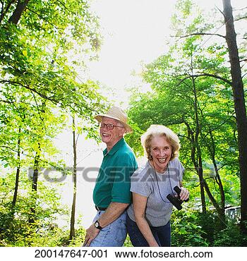 Stock Photography - senior couple 
standing back 
to back in woods, 
laughing. fotosearch 
- search stock 
photos, pictures, 
images, and photo 
clipart