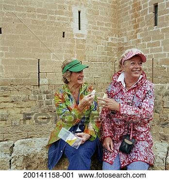 Stock Photography - two mature women 
sitting outdoors, 
holding sandwiches, 
laughing. fotosearch 
- search stock 
photos, pictures, 
images, and photo 
clipart