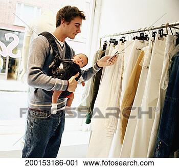 Stock Photography - man carrying baby 
girl (3-9 months), 
looking at price 
tag in shop. fotosearch 
- search stock 
photos, pictures, 
images, and photo 
clipart