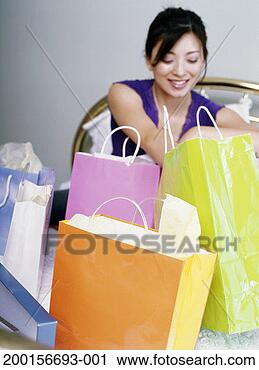Stock Photography - young woman looking 
into shopping 
bags (focus on 
bags in foreground). 
fotosearch - search 
stock photos, 
pictures, images, 
and photo clipart