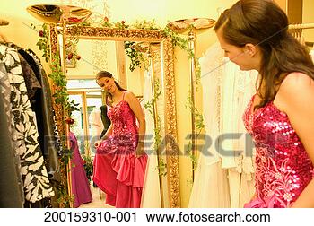 Stock Photography - young woman wearing 
formal dress, 
in front of mirror 
in clothes shop. 
fotosearch - search 
stock photos, 
pictures, images, 
and photo clipart