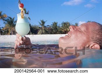 Stock Photography - man relaxing in 
sea holding tropical 
drink, smiling, 
side view. fotosearch 
- search stock 
photos, pictures, 
images, and photo 
clipart