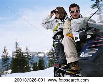 Stock Photography - couple on snowmobile, 
woman using binoculars 
while man looks 
at map. fotosearch 
- search stock 
photos, pictures, 
images, and photo 
clipart