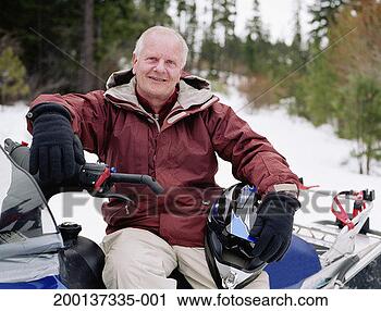 Stock Photography - mature man sitting 
on snowmobile, 
holding helmet, 
portrait. fotosearch 
- search stock 
photos, pictures, 
images, and photo 
clipart