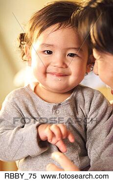Stock Image - an asian baby 
playfully smiles 
while being held 
by his mother. 
fotosearch - search 
stock photos, 
pictures, images, 
and photo clipart