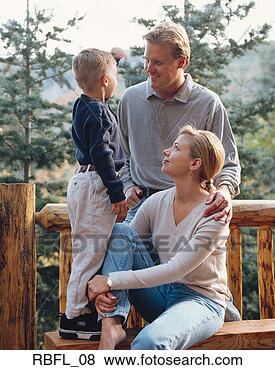 Stock Photo - small family pose 
on a wooden bench 
at their mountain 
cabin. fotosearch 
- search stock 
photos, pictures, 
images, and photo 
clipart