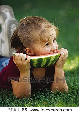 Stock Image - a cute caucasian 
girl eats a large 
piece of watermelon 
while lying in. 
fotosearch - search 
stock photos, 
pictures, images, 
and photo clipart