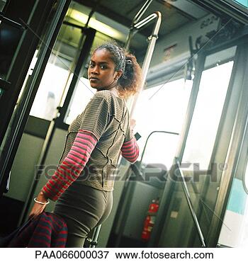 Picture - young woman holding 
rail, getting 
on bus, looking 
back over shoulder. 
fotosearch - search 
stock photos, 
pictures, images, 
and photo clipart