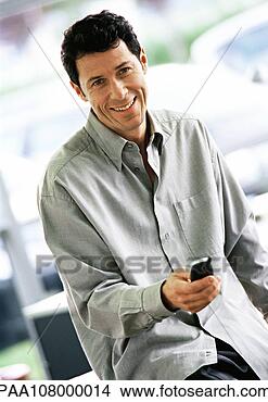 Stock Photo - man holding cell 
phone in front 
of him, smiling, 
waist up. fotosearch 
- search stock 
photos, pictures, 
images, and photo 
clipart