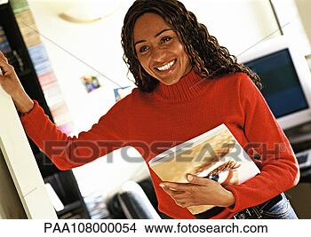 Stock Photo - woman holding 
catalog in office, 
smiling. fotosearch 
- search stock 
photos, pictures, 
images, and photo 
clipart