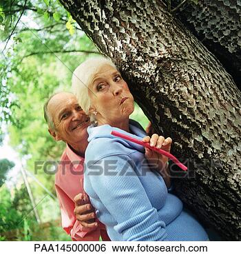 Stock Photo - mature man and 
woman standing 
behind tree. fotosearch 
- search stock 
photos, pictures, 
images, and photo 
clipart