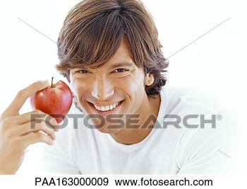 Stock Photograph - young man holding 
apple, looking 
into camera, portrait. 
fotosearch - search 
stock photos, 
pictures, images, 
and photo clipart