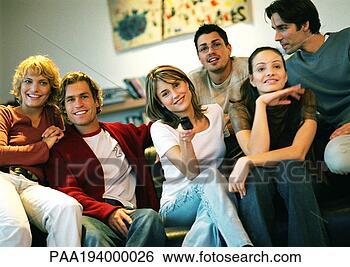 Stock Photo - people sitting 
together on couch, 
one woman holding 
remote. fotosearch 
- search stock 
photos, pictures, 
images, and photo 
clipart