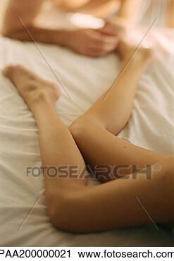 Stock Photography - on bed, woman's 
legs, man holding 
her foot, close 
up. fotosearch 
- search stock 
photos, pictures, 
images, and photo 
clipart