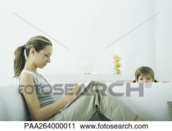 Stock Photography - young woman sitting 
on sofa writing 
on notepad,  girl 
peeking over. 
fotosearch - search 
stock photos, 
pictures, images, 
and photo clipart