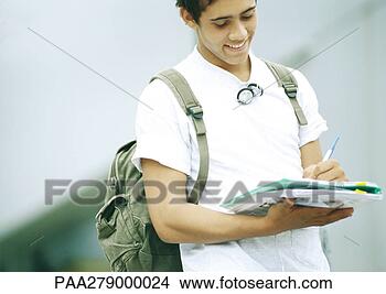 Stock Photo - male student standing 
and writing on 
folder. fotosearch 
- search stock 
photos, pictures, 
images, and photo 
clipart