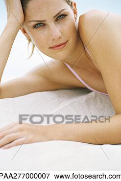 Picture - young woman lying 
on sand, leaning 
on elbow, looking 
at camera. fotosearch 
- search stock 
photos, pictures, 
images, and photo 
clipart