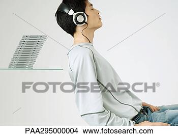 Stock Photo - young man listening 
to headphones, 
sitting in front 
of stack of cds. 
fotosearch - search 
stock photos, 
pictures, images, 
and photo clipart