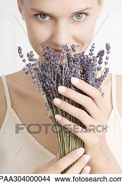 Stock Photo - woman smelling 
bunch of lavender, 
looking at camera. 
fotosearch - search 
stock photos, 
pictures, images, 
and photo clipart
