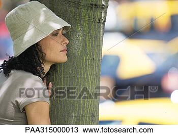 Stock Photo - young woman standing 
next to tree. 
fotosearch - search 
stock photos, 
pictures, images, 
and photo clipart