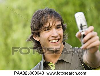 Stock Photo - young man holding 
up cell phone 
and smiling. fotosearch 
- search stock 
photos, pictures, 
images, and photo 
clipart