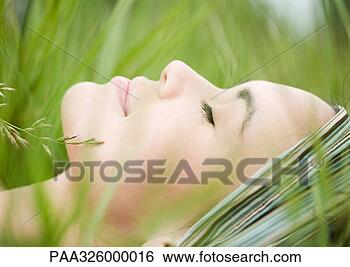 Stock Photo - young woman lying 
in grass, close-up 
of face. fotosearch 
- search stock 
photos, pictures, 
images, and photo 
clipart