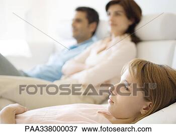 Picture - girl reclining 
on sofa, parents 
in background. 
fotosearch - search 
stock photos, 
pictures, images, 
and photo clipart