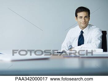 Picture - businessman sitting 
at desk, smiling 
at camera. fotosearch 
- search stock 
photos, pictures, 
images, and photo 
clipart
