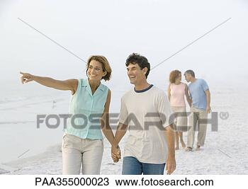 Stock Photo - mature couple 
walking on beach, 
woman pointing 
to distance. fotosearch 
- search stock 
photos, pictures, 
images, and photo 
clipart