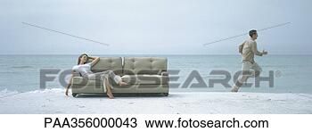 Stock Photo - on beach, woman 
reclining on sofa 
while man runs 
away. fotosearch 
- search stock 
photos, pictures, 
images, and photo 
clipart