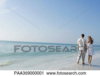 Stock Photography - couple walking 
alongside water 
on beach. fotosearch 
- search stock 
photos, pictures, 
images, and photo 
clipart