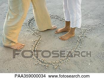 Stock Photo - woman standing 
in heart drawn 
in sand,  man 
stepping into 
heart. fotosearch 
- search stock 
photos, pictures, 
images, and photo 
clipart