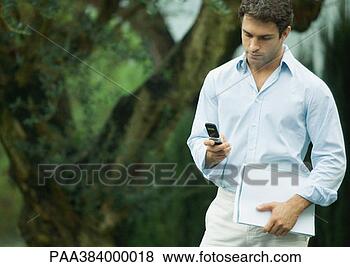 Stock Photo - man using cell 
phone outdoors, 
holding documents. 
fotosearch - search 
stock photos, 
pictures, images, 
and photo clipart