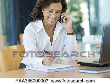 Picture - businesswoman 
working at desk 
with cell phone. 
fotosearch - search 
stock photos, 
pictures, images, 
and photo clipart
