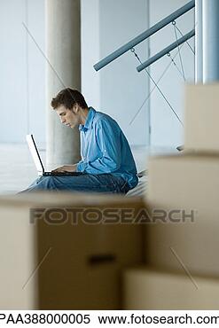 Stock Image - businessman using 
laptop, cardboard 
boxes in foreground. 
fotosearch - search 
stock photos, 
pictures, images, 
and photo clipart
