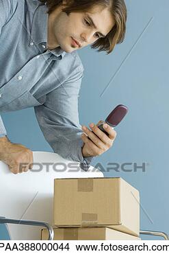 Stock Photo - man leaning against 
chair,  looking 
at cell phone, 
 cardboard boxes. 
fotosearch - search 
stock photos, 
pictures, images, 
and photo clipart