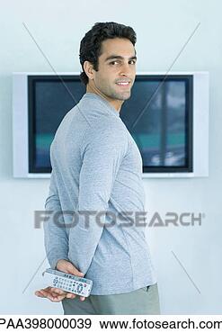 Stock Photograph - man standing in 
front of widescreen 
tv,  holding two 
remote controls. 
fotosearch - search 
stock photos, 
pictures, images, 
and photo clipart