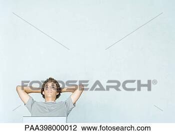Stock Photo - young man sitting 
with hands behind 
head,  looking 
up,  partial view. 
fotosearch - search 
stock photos, 
pictures, images, 
and photo clipart
