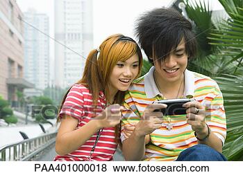 Banco de Imagem - adolescente,  
par,  tocando, 
 handheld,  vídeo, 
 jogo,  ao ar 
livre. fotosearch 
- busca de fotos, 
imagens e clipart