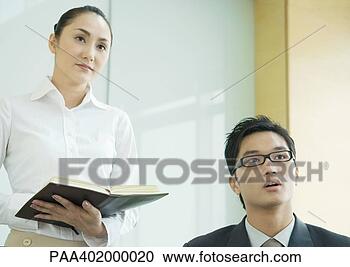 Stock Photography - business executive 
and woman holding 
agenda, both looking 
out of frame. 
fotosearch - search 
stock photos, 
pictures, images, 
and photo clipart