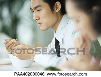 Stock Photo - businessman eating 
with chopsticks, 
looking away. 
fotosearch - search 
stock photos, 
pictures, images, 
and photo clipart