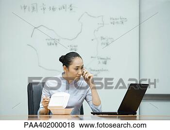 Banco de Imagem - executiva,  usando, 
 telefone,  olhar, 
 computador,  
enquanto,  comer. 
fotosearch - busca 
de fotos, imagens 
e clipart